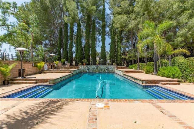 outdoor pool featuring fence and a patio