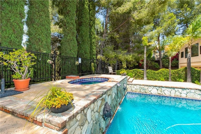 view of pool featuring an in-ground hot tub and fence