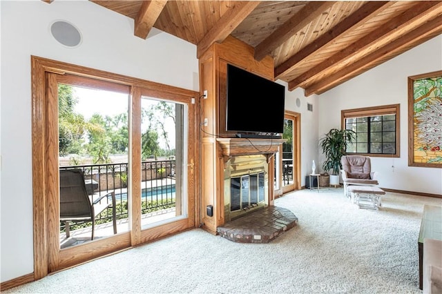 carpeted living area featuring healthy amount of natural light, a glass covered fireplace, wooden ceiling, and baseboards