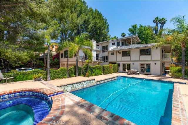 outdoor pool featuring an in-ground hot tub and a patio