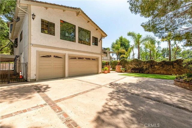 garage with concrete driveway and fence