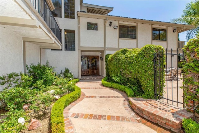 doorway to property featuring stucco siding, a gate, and french doors