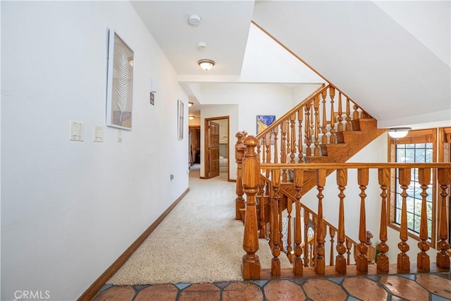 staircase featuring baseboards and carpet flooring