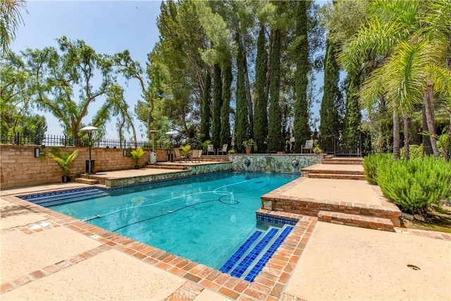 outdoor pool featuring fence and a patio area