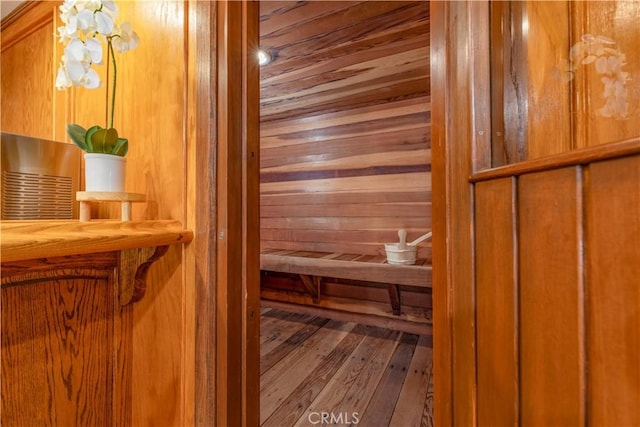 relaxing sauna with wooden walls, wood-type flooring, and wooden ceiling