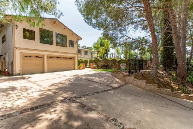 view of front of house with stucco siding, a garage, driveway, and fence