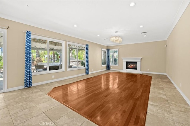 unfurnished living room with crown molding, light tile patterned floors, baseboards, a chandelier, and a glass covered fireplace