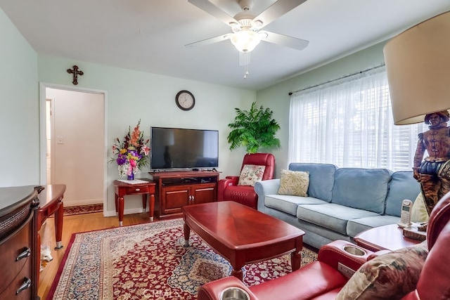 living area with light wood-style floors, ceiling fan, and baseboards