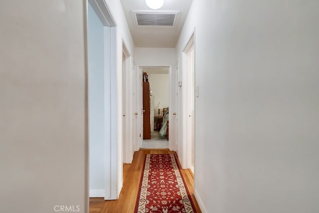 hall with light wood-type flooring and baseboards