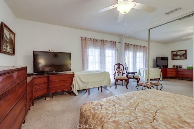 bedroom featuring light carpet, a closet, a ceiling fan, and an office area