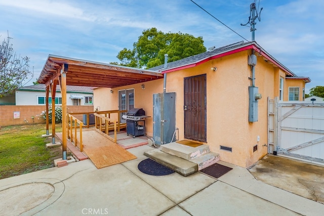 rear view of property with a gate, a patio area, entry steps, and stucco siding