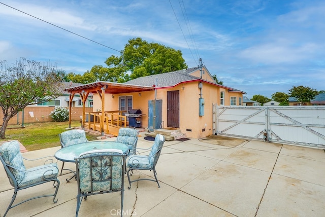 rear view of house with a gate, a patio area, stucco siding, outdoor dining space, and a pergola