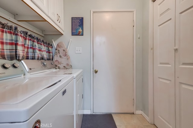 laundry area featuring separate washer and dryer, cabinet space, light tile patterned floors, and baseboards