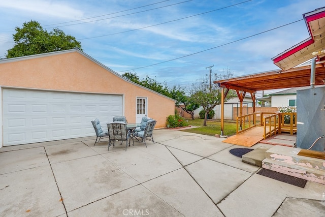 view of patio / terrace featuring fence, a detached garage, and an outbuilding