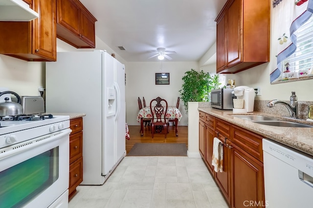 kitchen with white appliances, a sink, under cabinet range hood, a ceiling fan, and brown cabinets