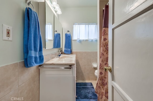 full bathroom featuring tile walls, toilet, vanity, and wainscoting