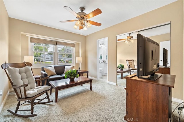 living area featuring a ceiling fan, baseboards, and light colored carpet