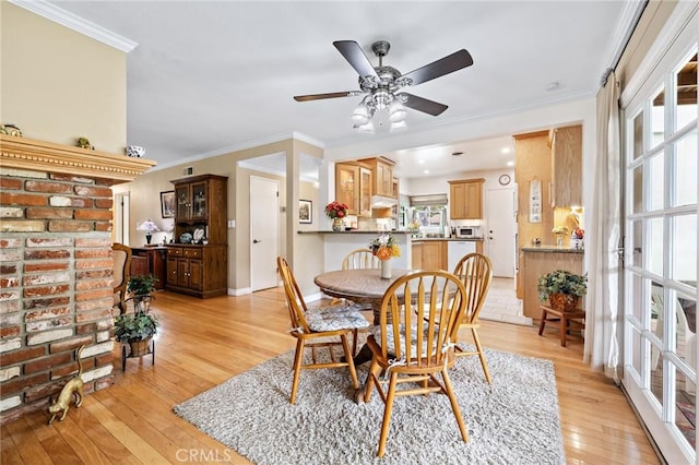 dining room featuring light wood finished floors, crown molding, plenty of natural light, ceiling fan, and baseboards