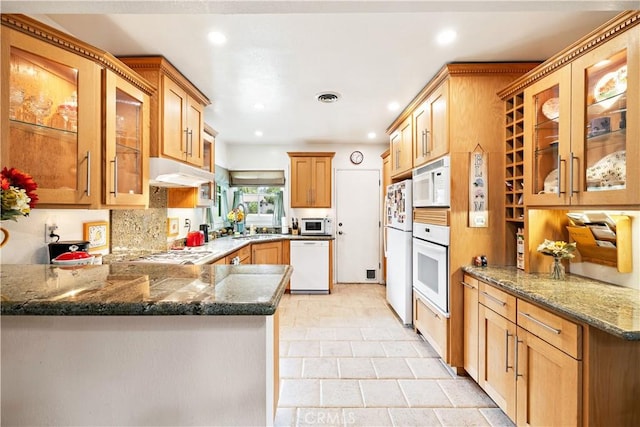 kitchen with white appliances, under cabinet range hood, a sink, recessed lighting, and glass insert cabinets