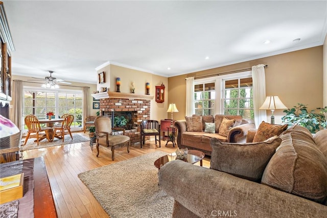 living room with plenty of natural light, wood-type flooring, a brick fireplace, a ceiling fan, and crown molding