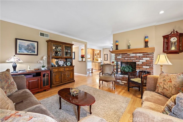 living room featuring ornamental molding, light wood-style floors, a brick fireplace, and recessed lighting