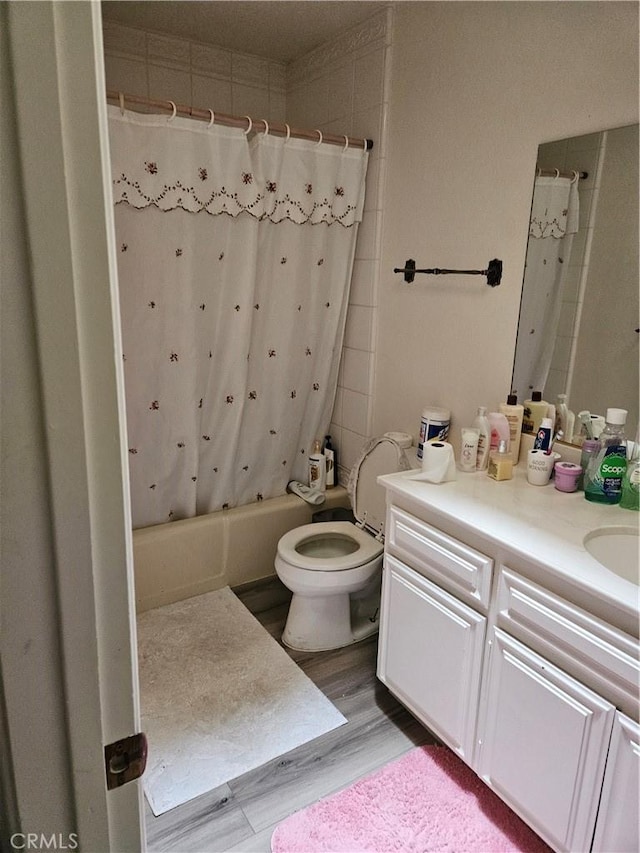 bathroom featuring wood finished floors, shower / bath combo with shower curtain, vanity, and toilet