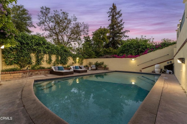pool at dusk featuring a patio and a fenced backyard