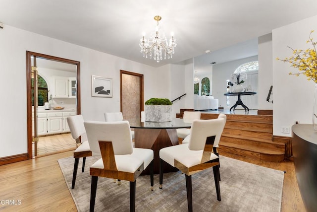 dining room with a chandelier, light wood finished floors, and baseboards