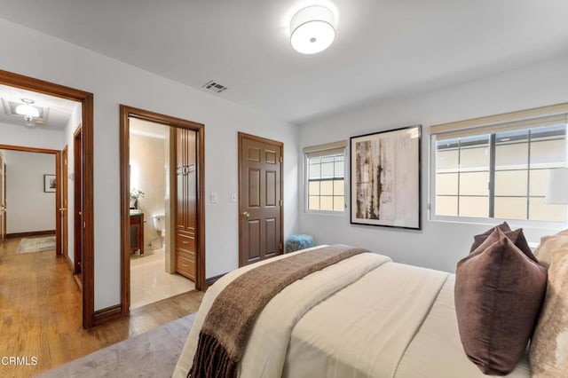 bedroom with light wood-style flooring and connected bathroom