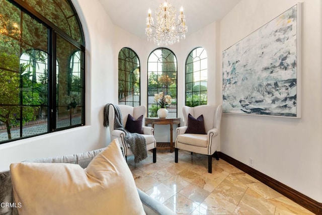 sitting room with baseboards, a chandelier, and stone tile flooring