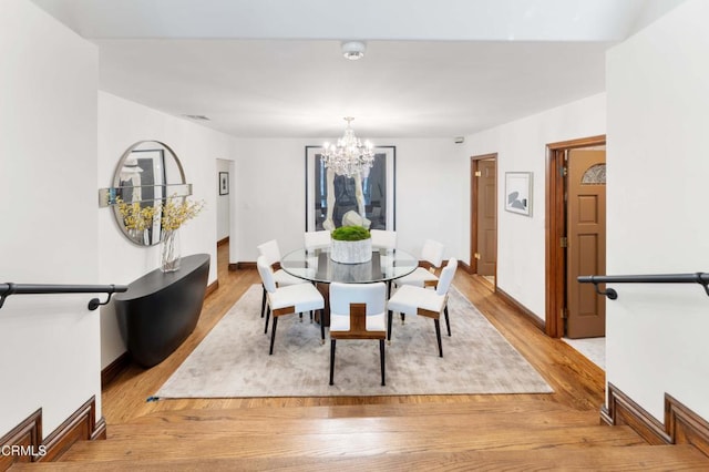 dining area with a chandelier, light wood finished floors, and baseboards