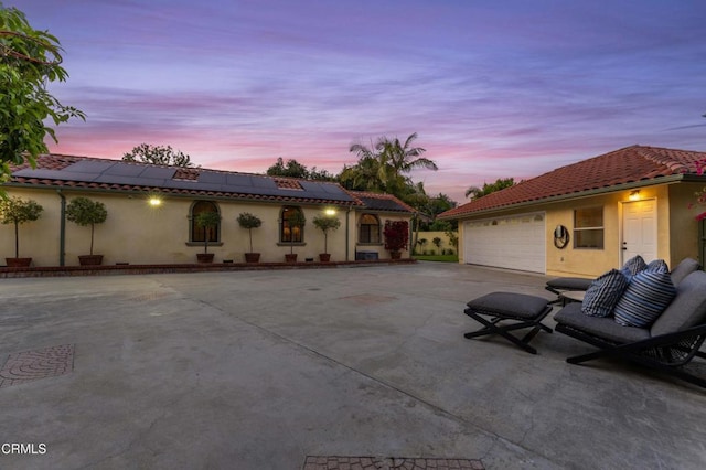 patio terrace at dusk with concrete driveway and a garage