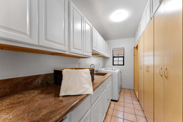 clothes washing area with washing machine and clothes dryer, cabinet space, and light tile patterned flooring