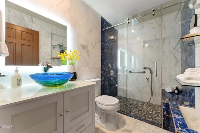 bathroom featuring tile walls, a marble finish shower, toilet, vanity, and marble finish flooring