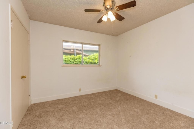 carpeted empty room with a textured ceiling, ceiling fan, and baseboards