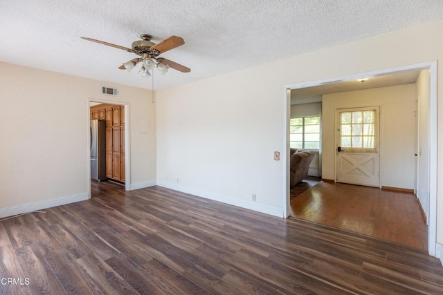 empty room featuring dark wood-style floors, a ceiling fan, a textured ceiling, and baseboards