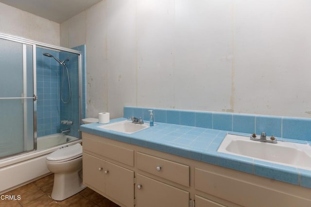 bathroom with toilet, double vanity, tile patterned floors, and shower / bath combination with glass door