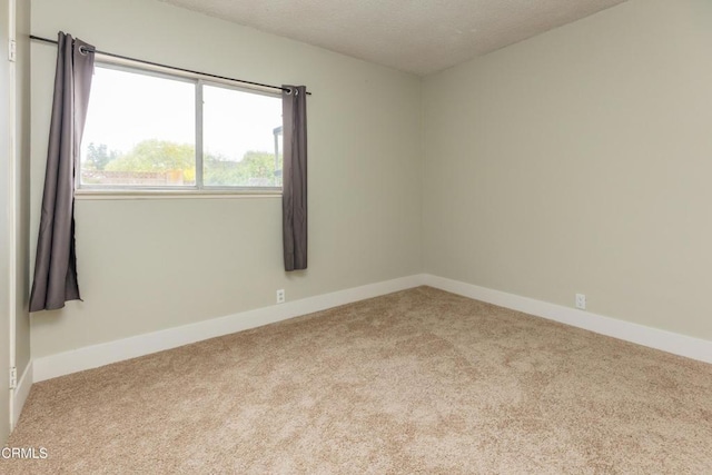 empty room featuring carpet flooring, baseboards, and a textured ceiling