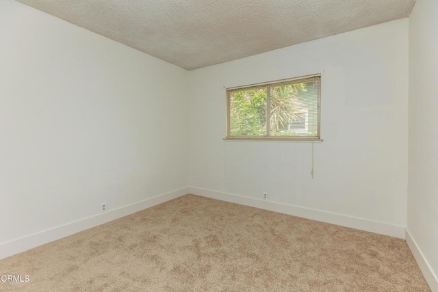 carpeted spare room with a textured ceiling and baseboards