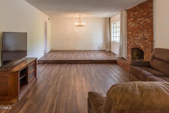 living area with a chandelier, wood finished floors, a brick fireplace, and baseboards