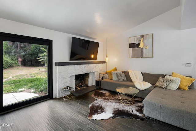living area with vaulted ceiling, wood finished floors, and a stone fireplace