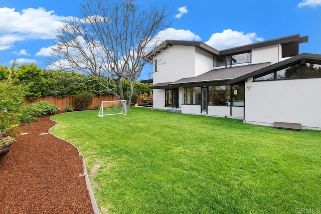rear view of house featuring fence, stucco siding, and an area for sports