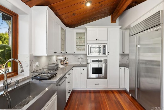 kitchen featuring built in appliances, a sink, wooden ceiling, white cabinets, and tasteful backsplash