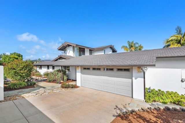 traditional-style home with a garage, stucco siding, and concrete driveway