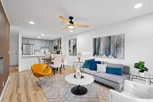 living area with light wood-style floors, recessed lighting, ceiling fan, and baseboards