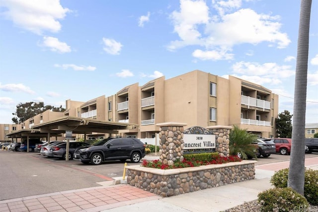 view of apartment building / complex featuring covered and uncovered parking