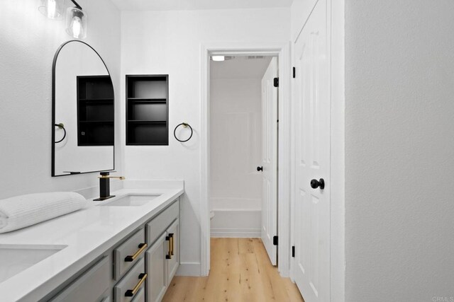 bathroom with wood finished floors and double vanity