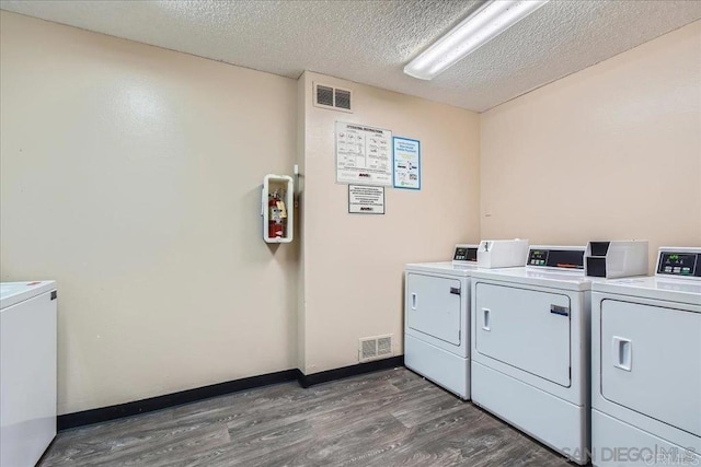 shared laundry room with washing machine and dryer, dark wood-type flooring, a textured ceiling, and baseboards