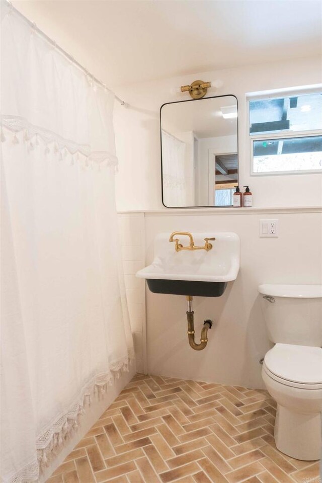 25860 Oakwood St, Idyllwild, CA 92549 - full bath featuring brick flooring, toilet, a shower with shower curtain, and a sink