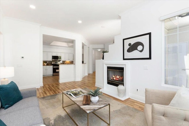 12370 Carmel Country Rd Unit 305, San Diego, CA 92130 - living area with light wood-style floors, baseboards, a glass covered fireplace, recessed lighting, and ornamental molding